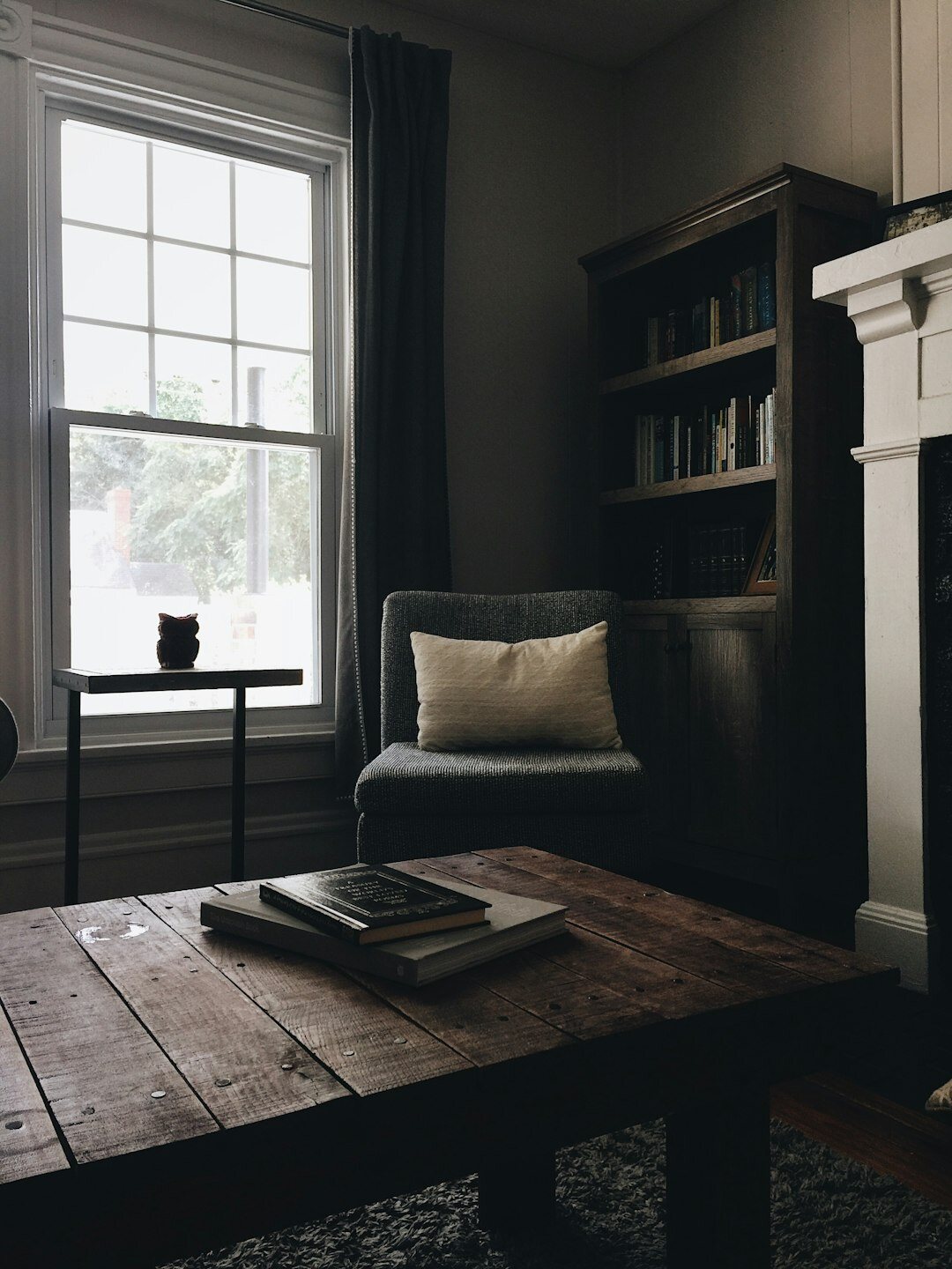 Cozy home study filled with bookshelves, an armchair and warm lamp light
