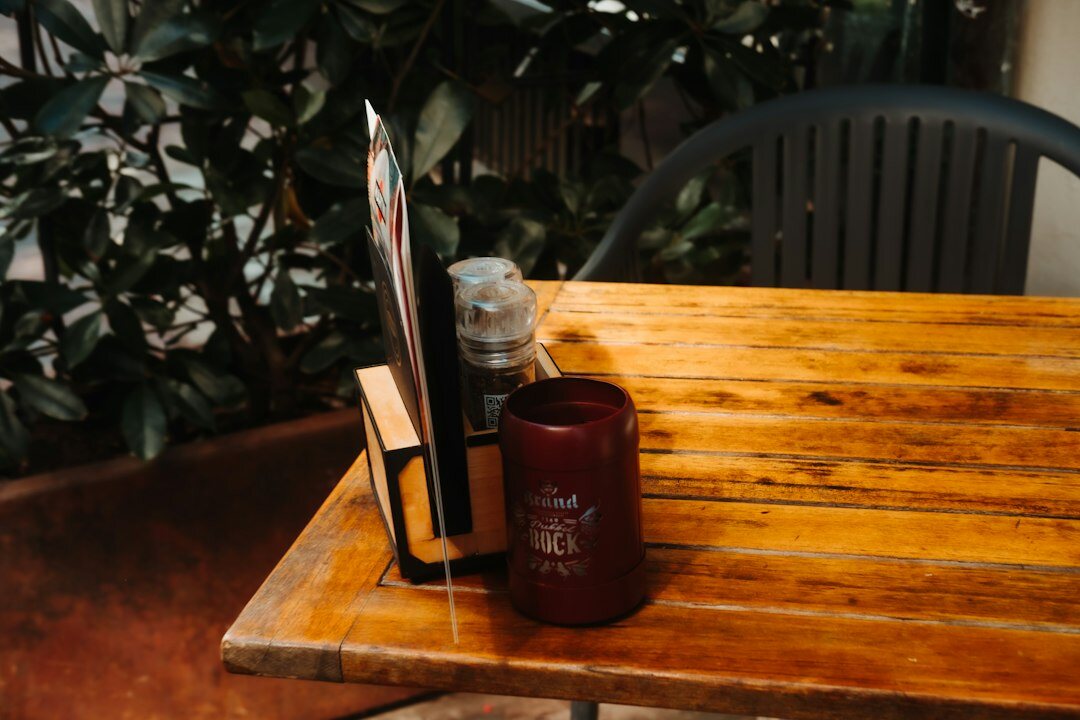 Stack of old hardcover mystery novels on a wooden table beside a candle